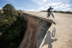 mountain biker jumping on edge of a cliff with shadow