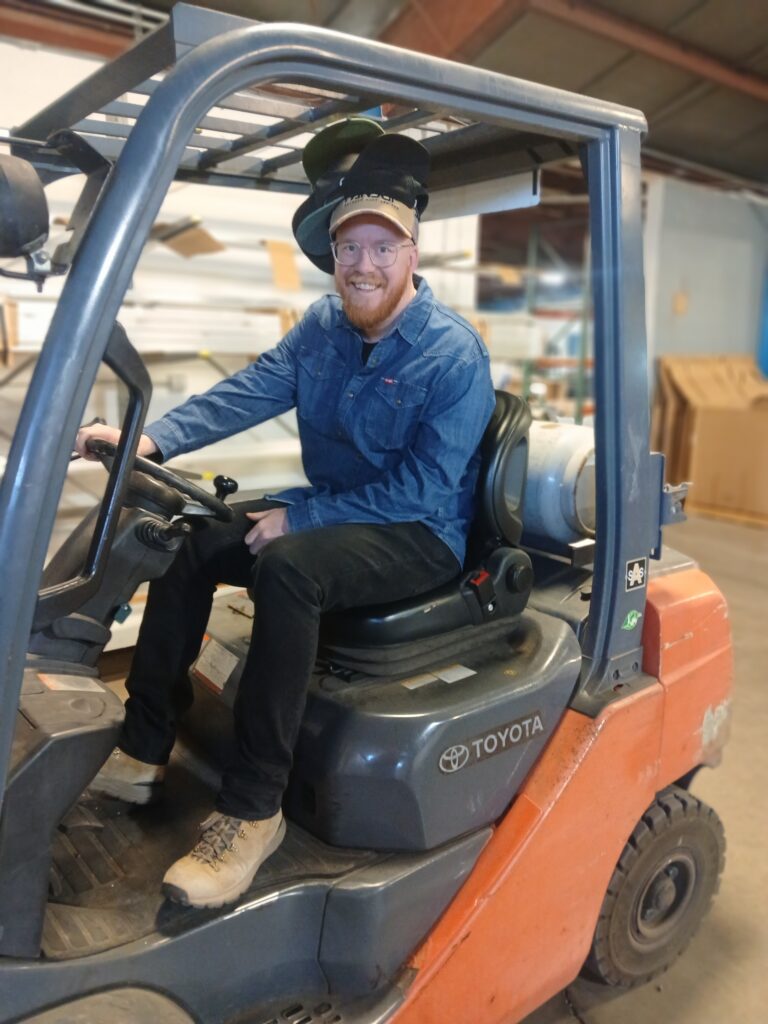 Eric on the fork lift wearing many hats.