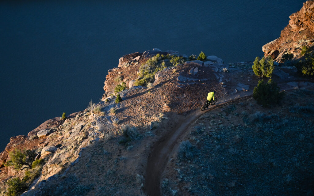 A rider over the Colorado River overlook, riding the Horsethief Bench trail.